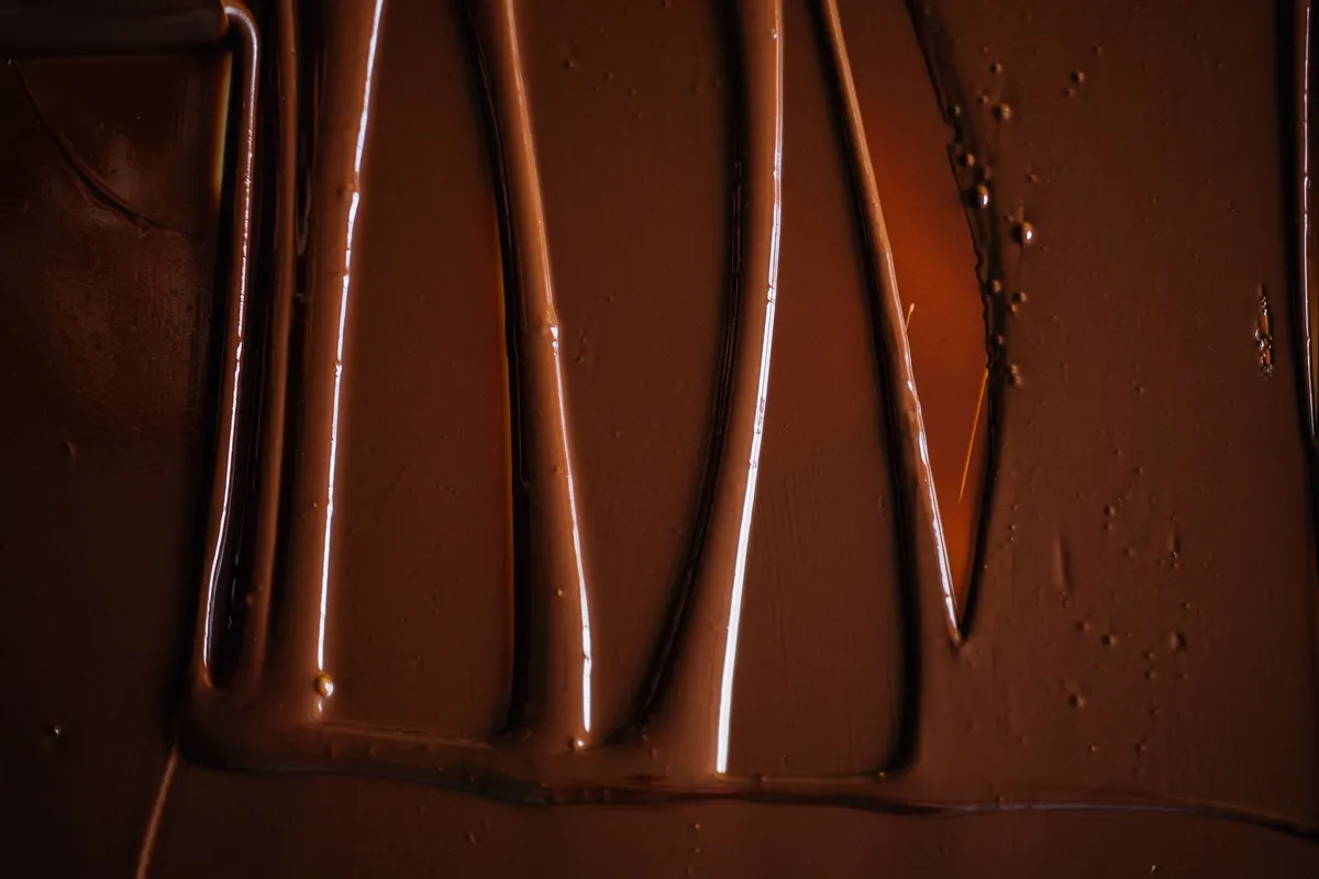 Chocolate temperado fluido espalhado sobre uma bancada em dobras brilhantes