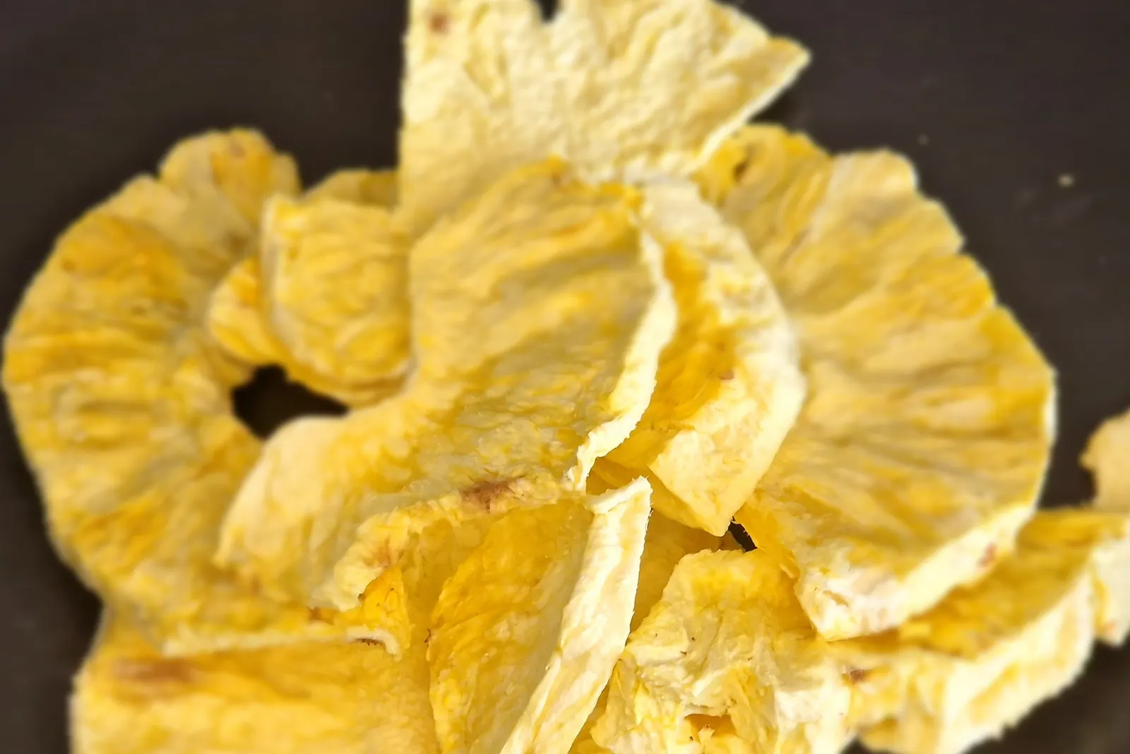 Rodelas de ananás liofilizado, pálidas e mates, mantendo a forma de anel completa