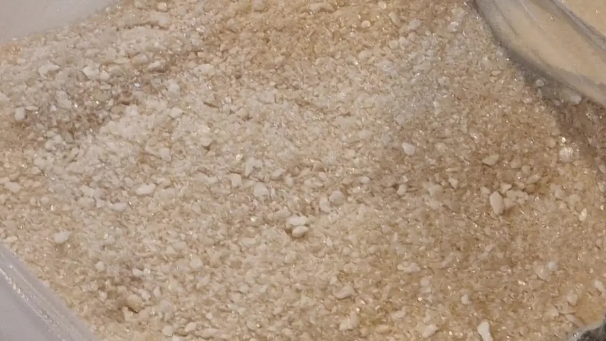 Grande plano de caldo de vaca liofilizado grosseiro, com partículas irregulares dourado-claras e fragmentos porosos visíveis