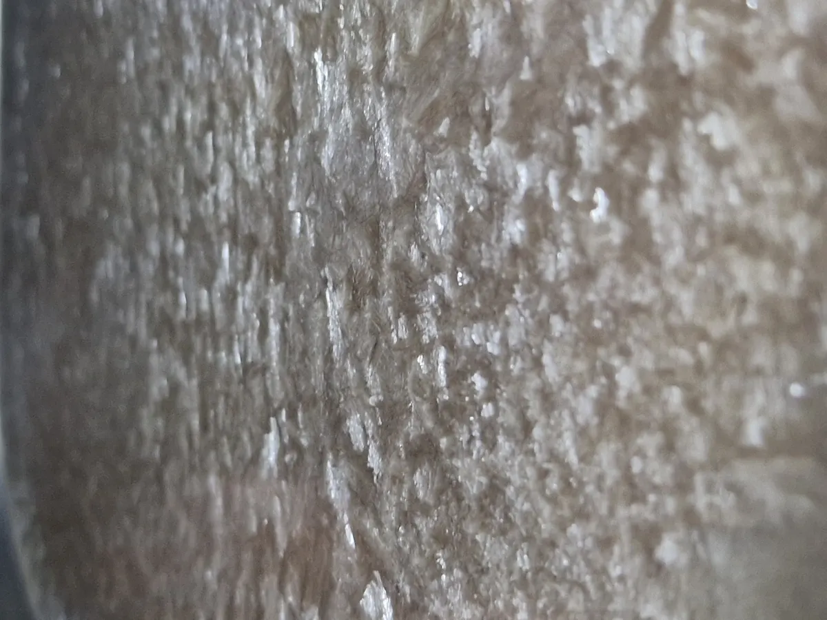 Grande plano extremo da superfície do caldo de vaca congelado a meio do ciclo, com cristais de gelo e uma matriz porosa visíveis